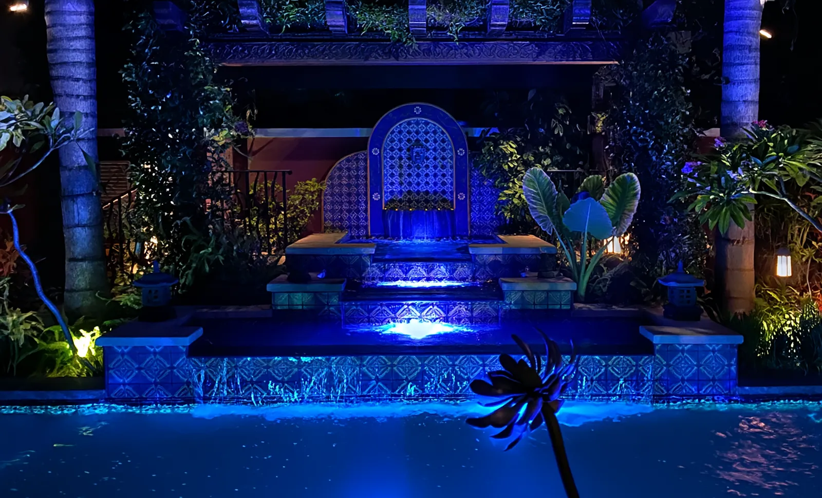 Beverly Hills pool, spa and tiled grotto waterfall lit in blue at night