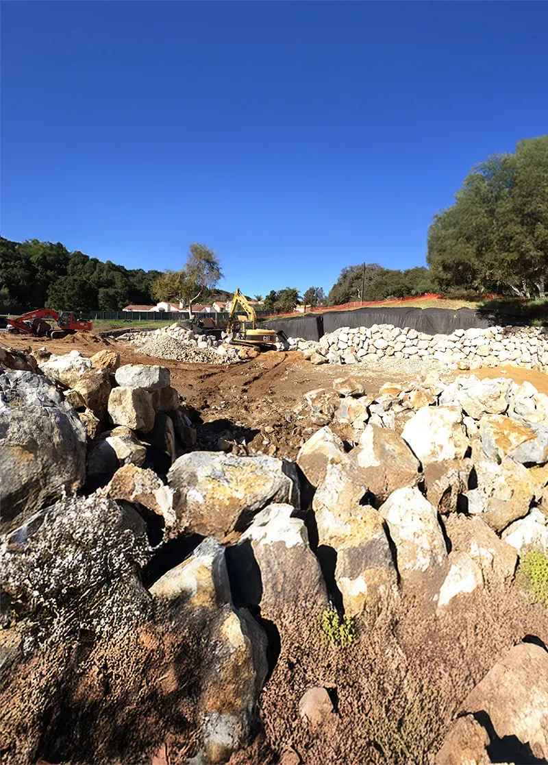 Boulders staged for a dry-stacked rockery wall on an estate site