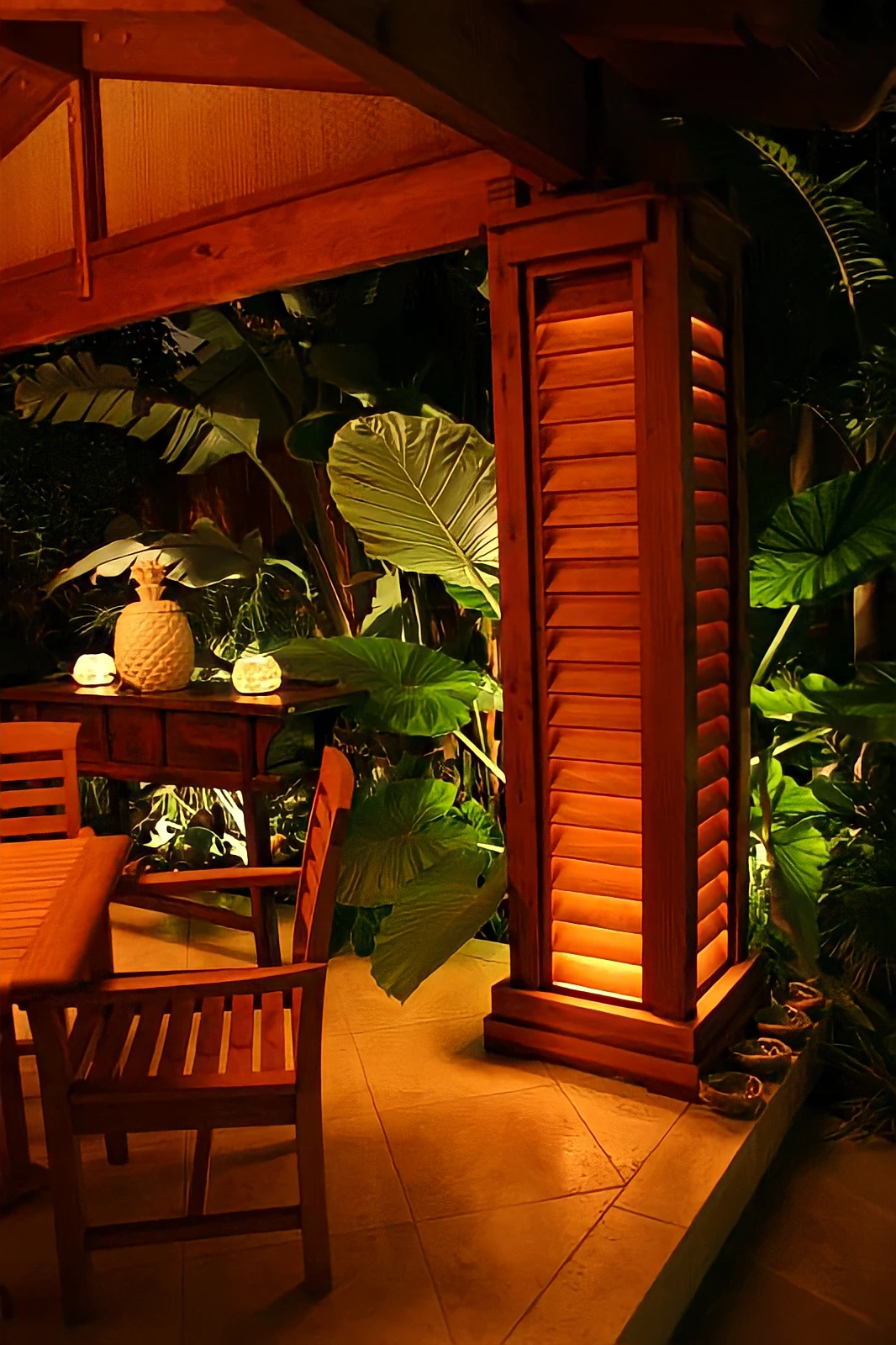 Illuminated redwood column and thatch-roof patio among tropical planting in Orange County
